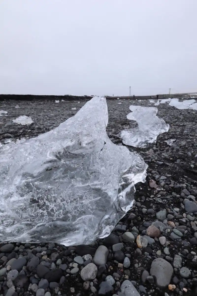 曇天の中でも黒い砂浜に横たわる氷は素敵